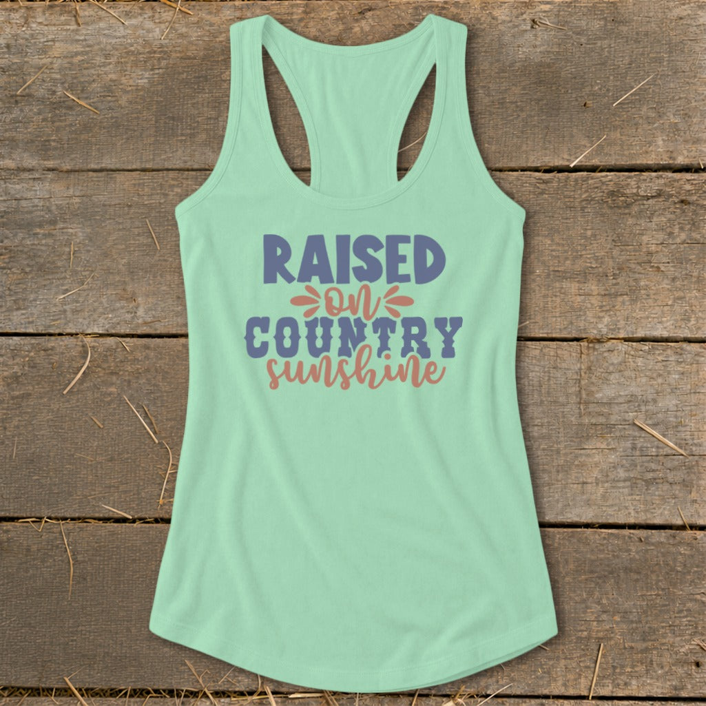 Light blue tank top with "RAISED ON COUNTRY sunshine" text design.
