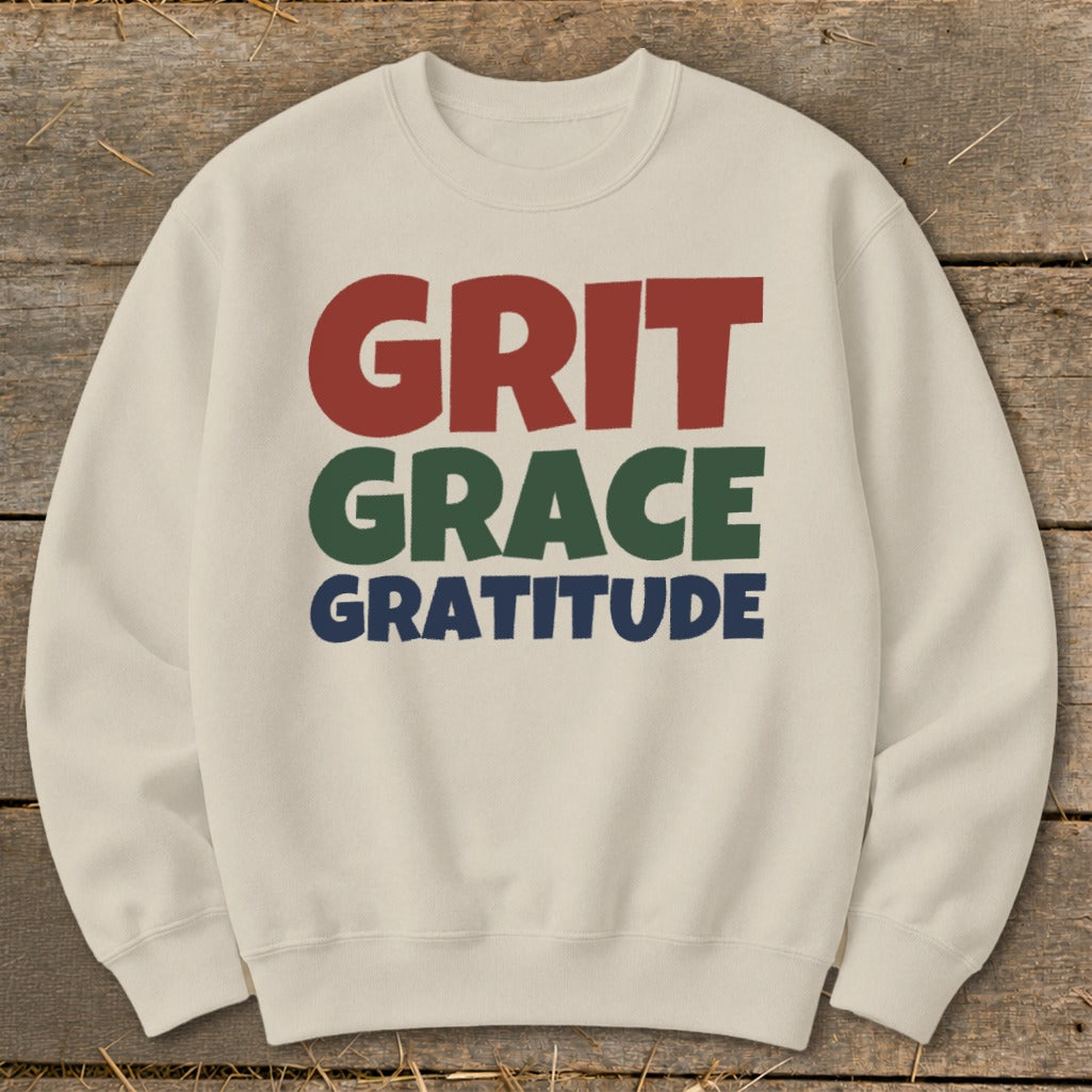 Cream crewneck sweatshirt featuring the red, green, and blue text GRIT GRACE GRATITUDE centered on the chest.