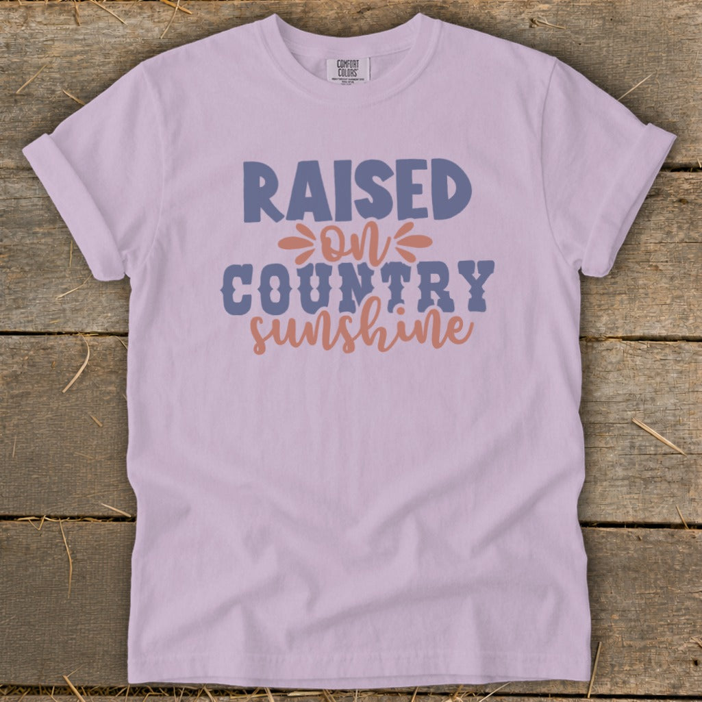 Light purple t-shirt with "Raised on Country Sunshine" graphic.