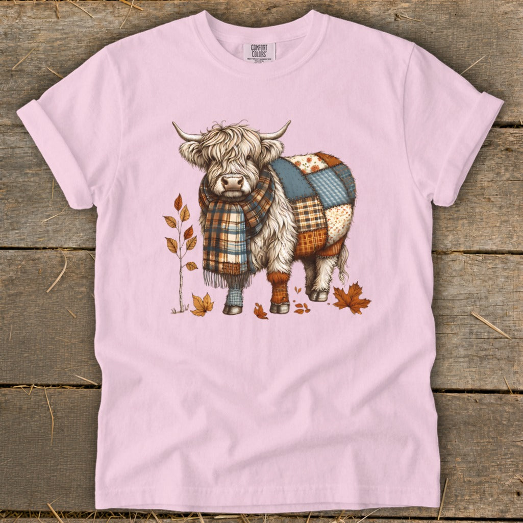 Highland cow graphic with patchwork body and plaid scarf on pink t-shirt.