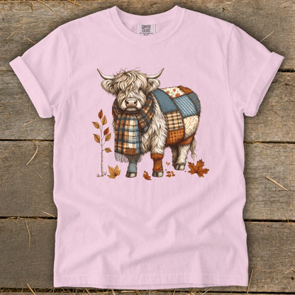 Highland cow graphic with patchwork body and plaid scarf on pink t-shirt.