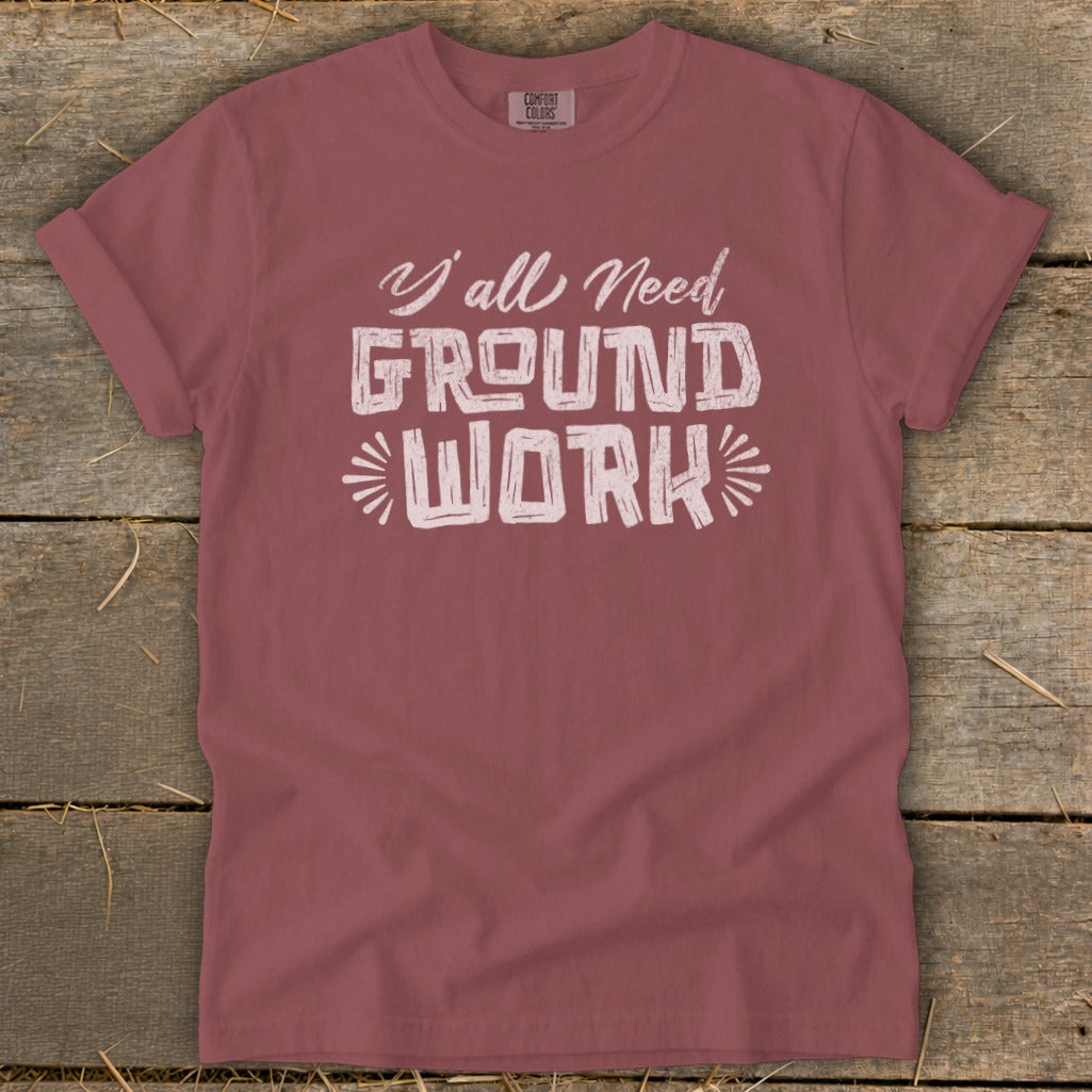Rose-colored t-shirt with "Y'all Need GROUND WORK" graphic.