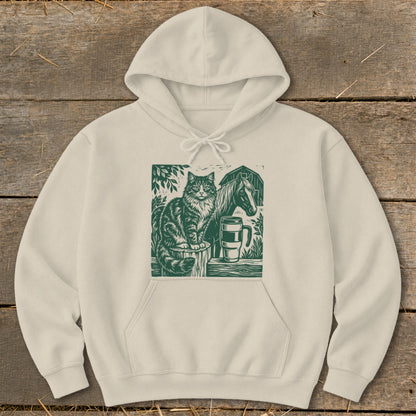 Cream hoodie with green linocut print of cat, horse, mug, and barn.