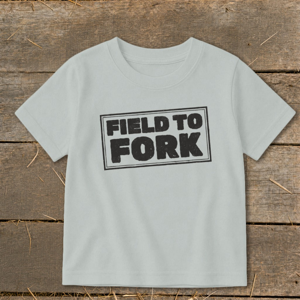 Light gray children's t-shirt featuring a black block-print graphic with the text FIELD TO FORK.
