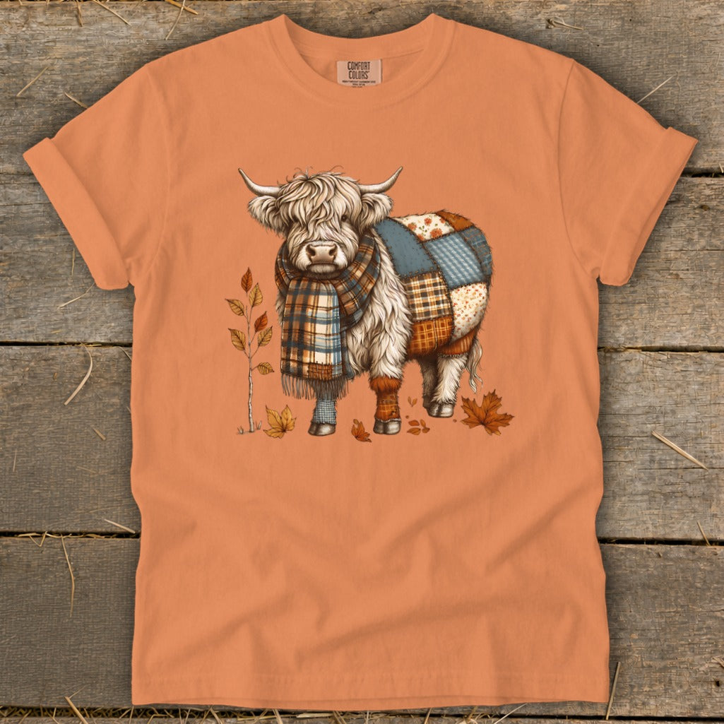 Orange t-shirt with a Highland cow wearing a plaid scarf and patchwork body.