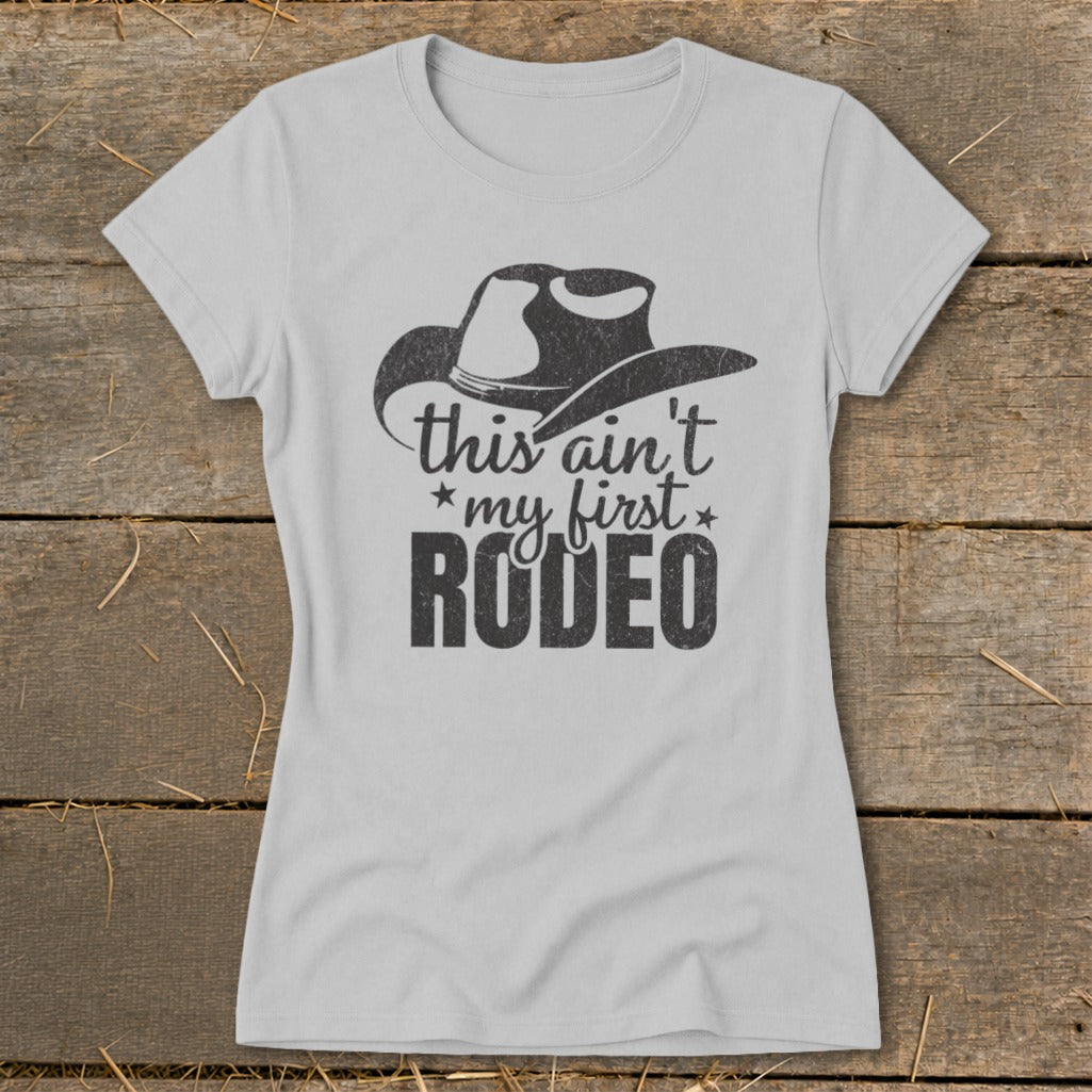 Light grey t-shirt with black distressed graphic of a cowboy hat and text reading "this ain't my first rodeo".