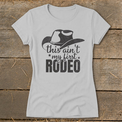 Light grey t-shirt with black distressed graphic of a cowboy hat and text reading "this ain't my first rodeo".