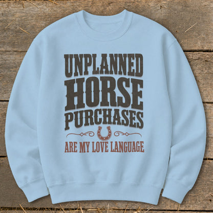Light blue sweatshirt with "Unplanned Horse Purchases Are My Love Language" text and horseshoe.