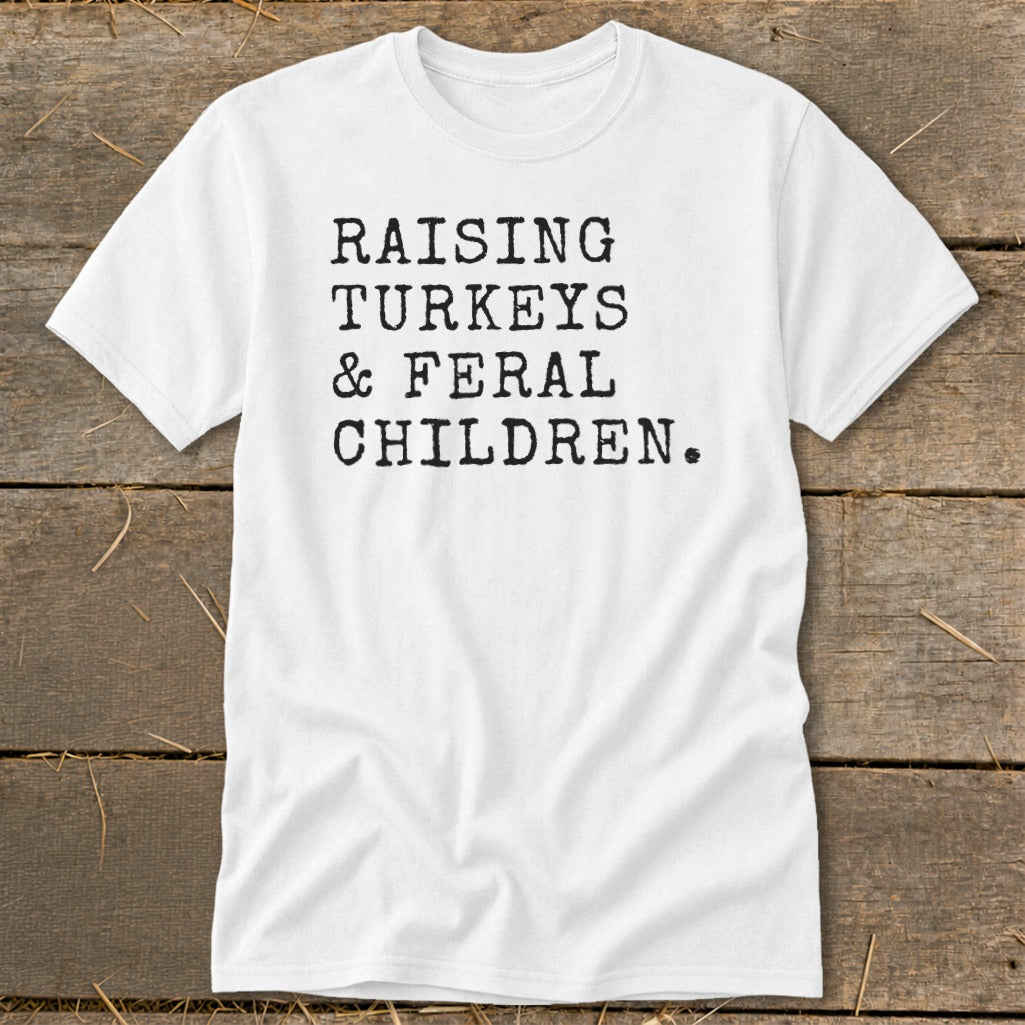 White t-shirt with black text reading "RAISING TURKEYS & FERAL CHILDREN."