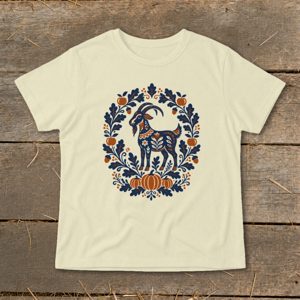 Cream-colored t-shirt featuring a folk art illustration of a goat surrounded by autumn leaves, pumpkins, and apples.