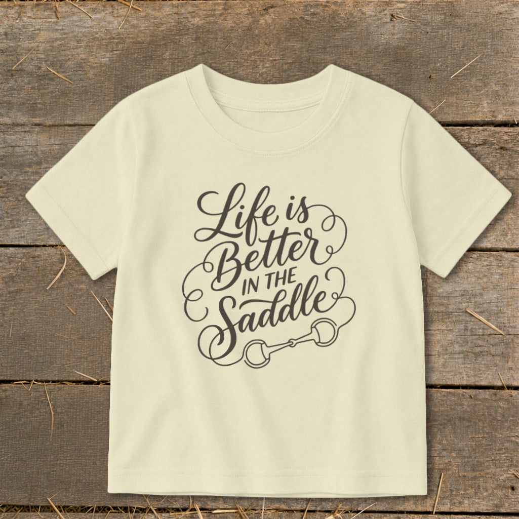 Cream t-shirt with "Life is Better In The Saddle" graphic and horse bit.
