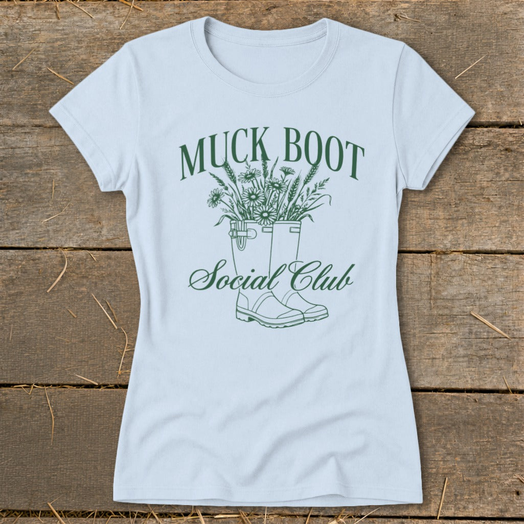 Light blue t-shirt with green "Muck Boot Social Club" text and boots with flowers graphic.