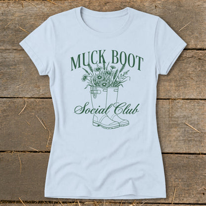 Light blue t-shirt with green "Muck Boot Social Club" text and boots with flowers graphic.