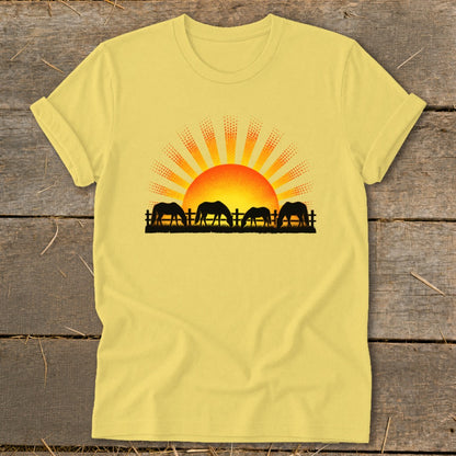 Yellow t-shirt with horses grazing at sunset graphic.
