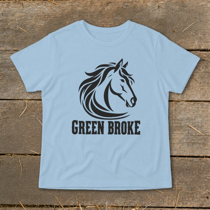Light blue crewneck t-shirt featuring a black graphic of a horse head and the text GREEN BROKE, laid flat on rustic wood.