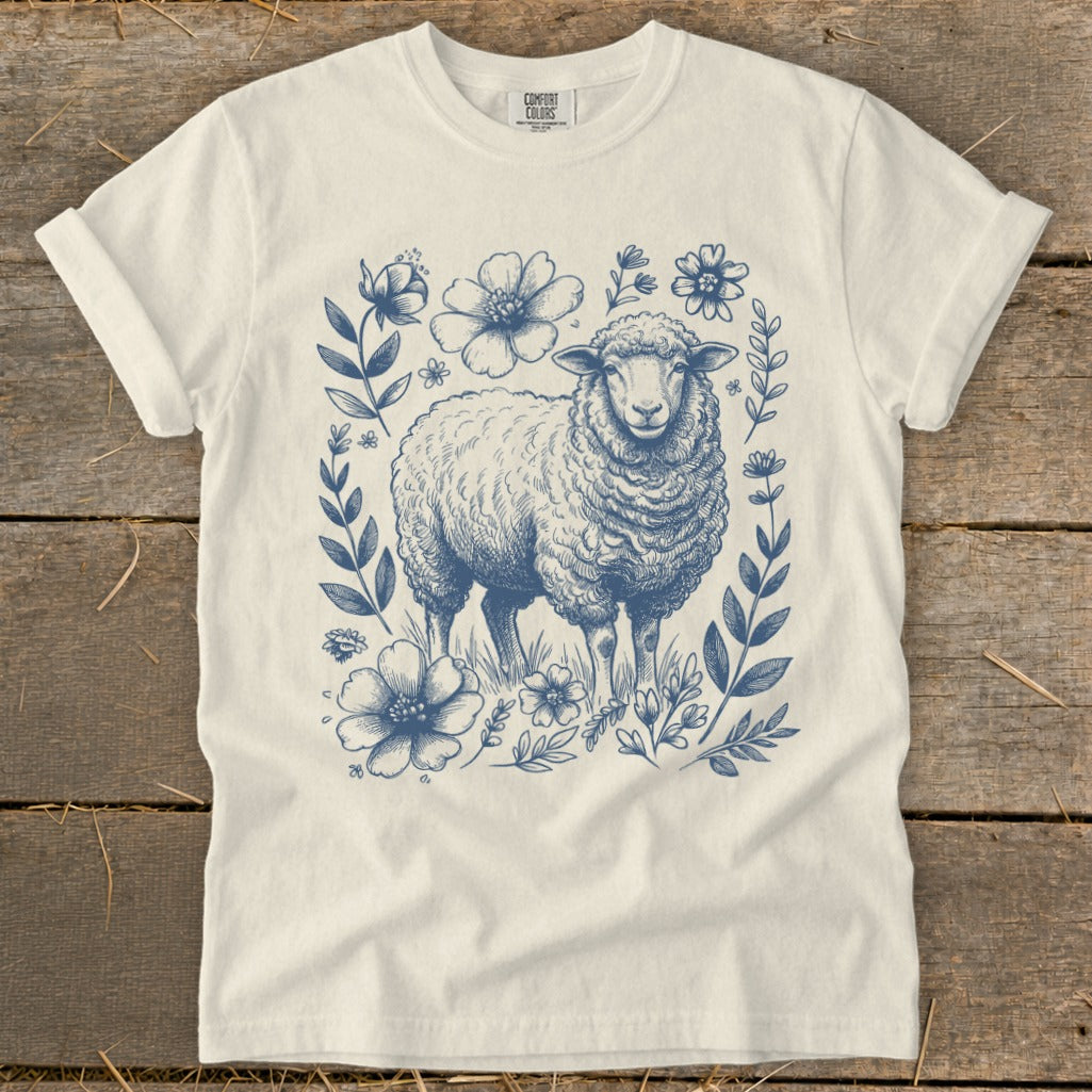 Cream t-shirt with a blue sketch of a sheep surrounded by flowers and foliage.