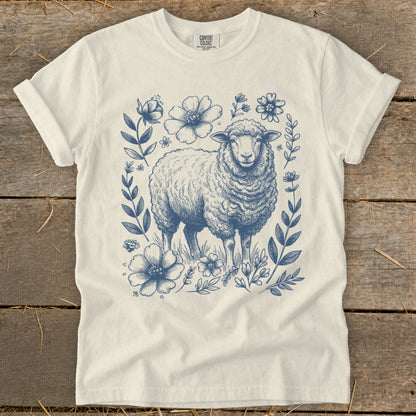 Cream t-shirt with a blue sketch of a sheep surrounded by flowers and foliage.