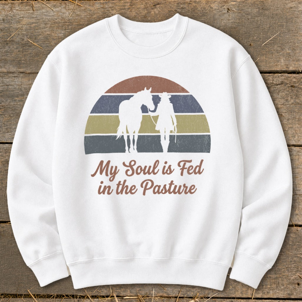 White sweatshirt with sunset graphic and text "My Soul is Fed in the Pasture".