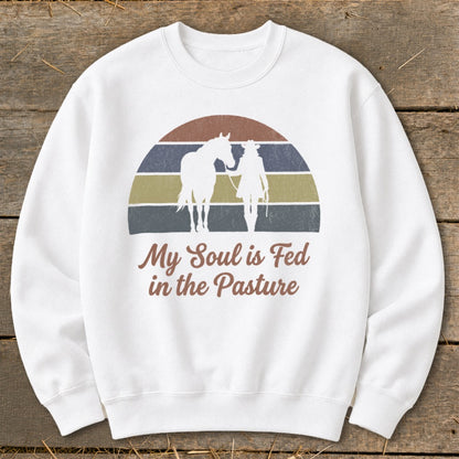 White sweatshirt with sunset graphic and text "My Soul is Fed in the Pasture".