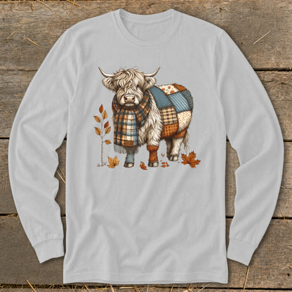Highland cow in a patchwork quilt pattern and plaid scarf with autumn leaves.
