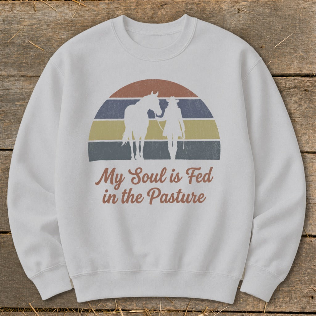 White sweatshirt with a vintage graphic of a horse and rider with text "My Soul is Fed in the Pasture".