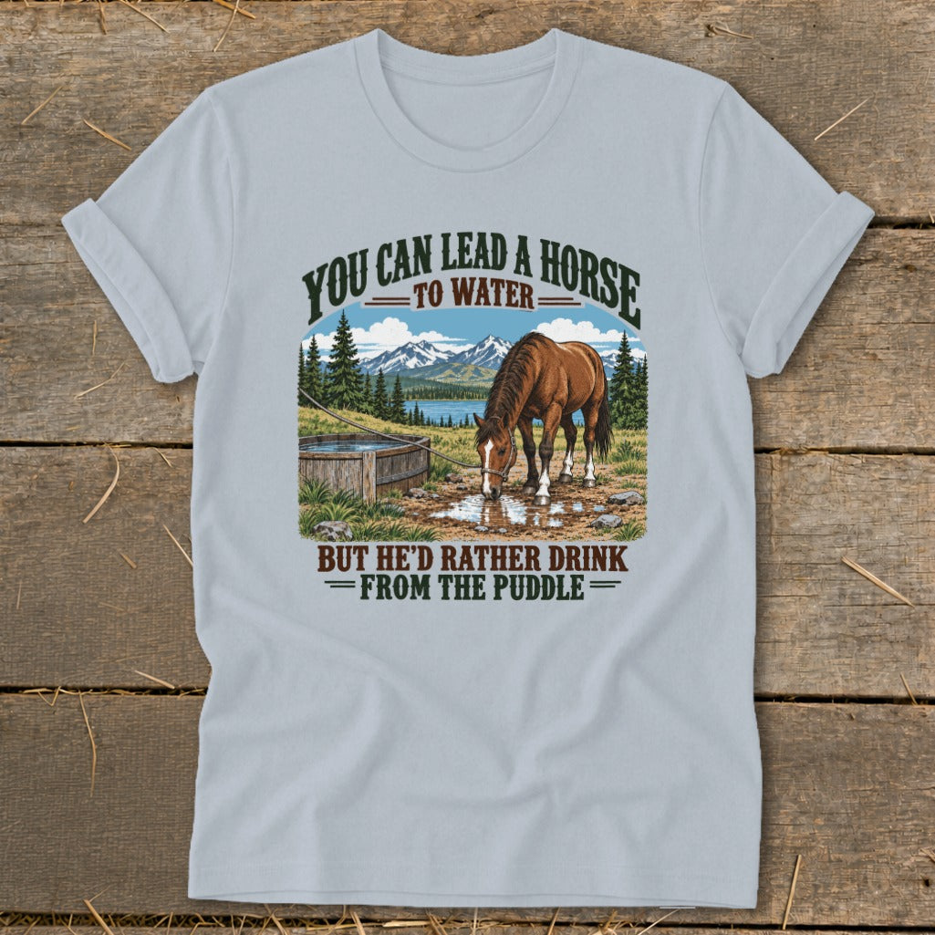 Light blue t-shirt featuring a horse drinking from a puddle with text above and below.