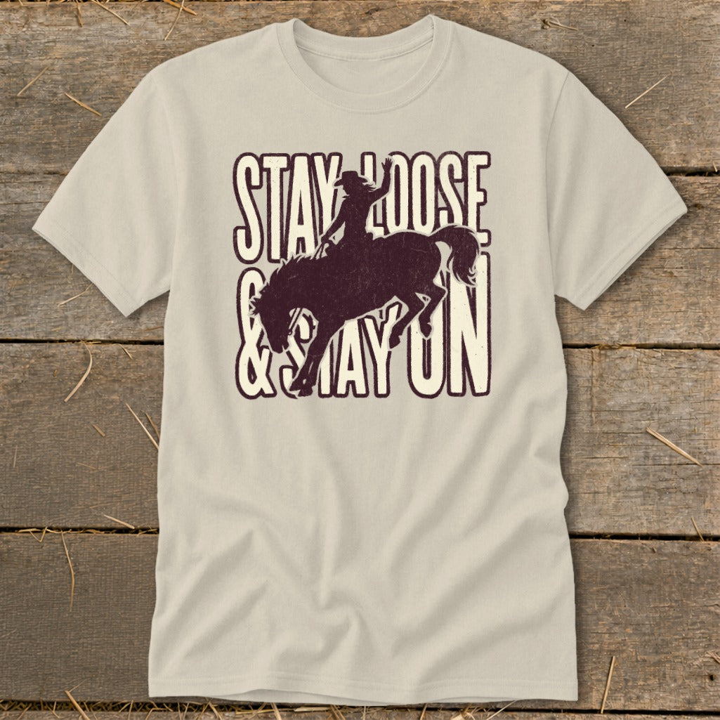 Light beige t-shirt with distressed graphic of a bronco rider and text "Stay Loose & Stay On."