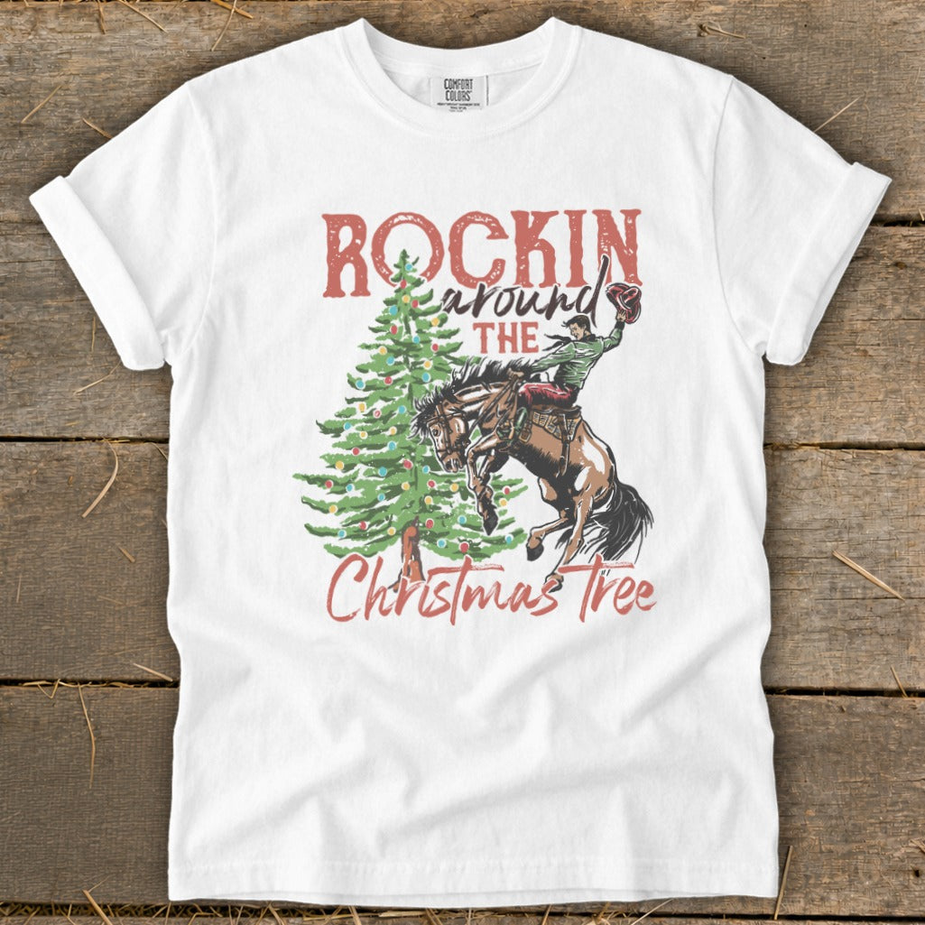 White t-shirt with graphic of cowboy on bucking horse near Christmas tree and text "Rockin' Around the Christmas Tree".