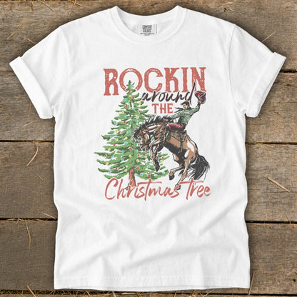 White t-shirt with graphic of cowboy on bucking horse near Christmas tree and text "Rockin' Around the Christmas Tree".