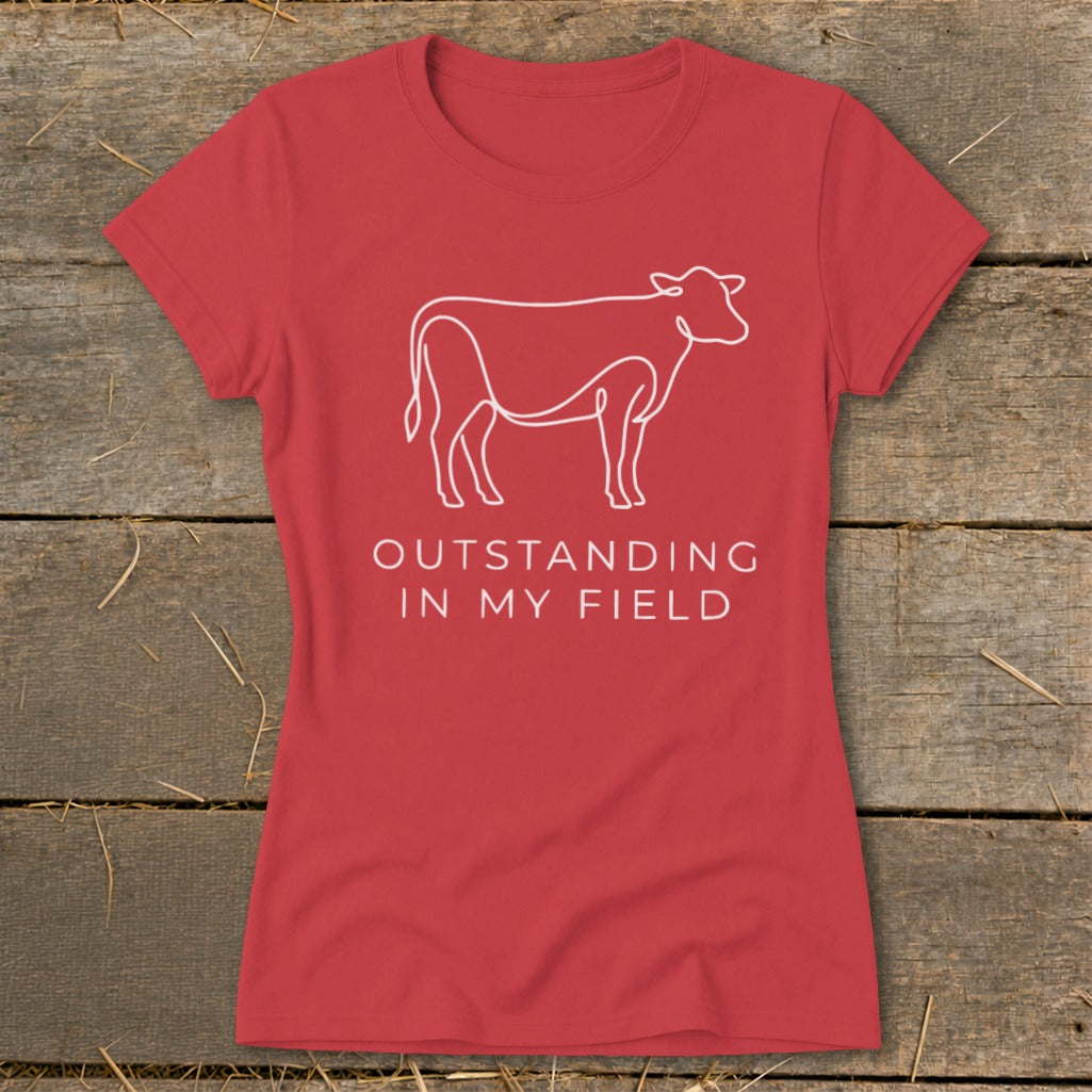 Red t-shirt with a white line drawing of a cow and text "OUTSTANDING IN MY FIELD."