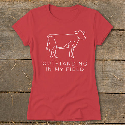 Red t-shirt with a white line drawing of a cow and text "OUTSTANDING IN MY FIELD."