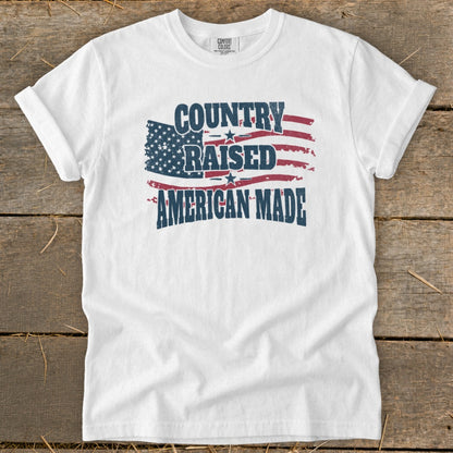 White t-shirt with distressed American flag graphic and text "COUNTRY RAISED AMERICAN MADE".