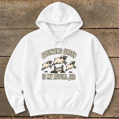 White hoodie with "COUNTING SHEEP IS MY ACTUAL JOB" text and jumping sheep graphic.