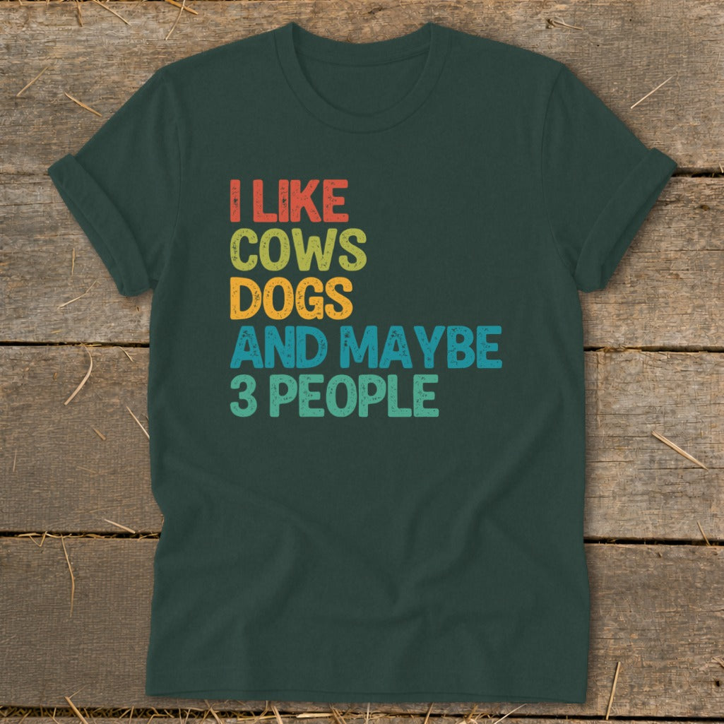 Dark green t-shirt with "I LIKE COWS DOGS AND MAYBE 3 PEOPLE" text in retro colors.