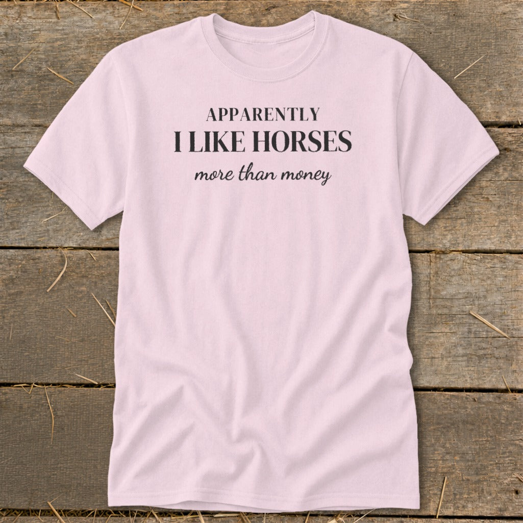 Pink t-shirt with black text "APPARENTLY I LIKE HORSES more than money".