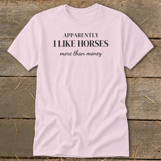 Pink t-shirt with black text "APPARENTLY I LIKE HORSES more than money".