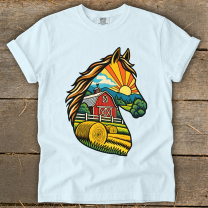 A light blue t-shirt with a colorful graphic of a horse head silhouette framing a farm landscape.
