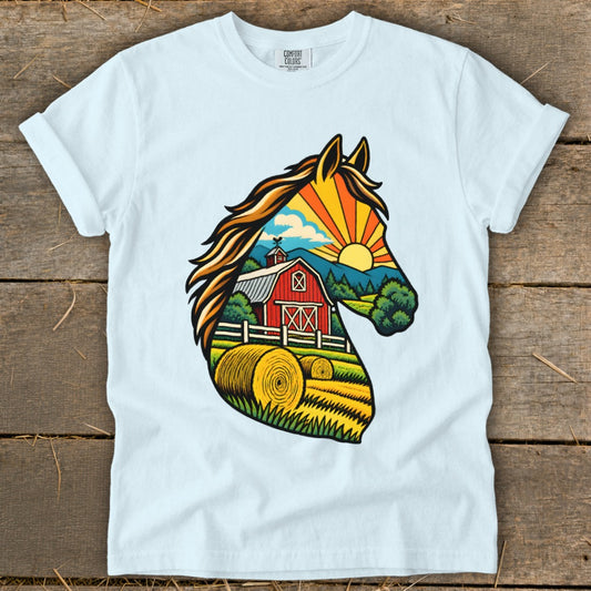 A light blue t-shirt with a colorful graphic of a horse head silhouette framing a farm landscape.