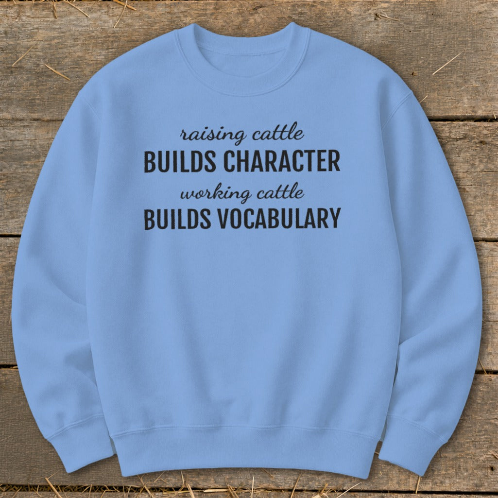Light blue sweatshirt with black text "raising cattle BUILDS CHARACTER working cattle BUILDS VOCABULARY".