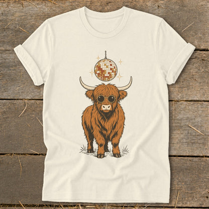 Highland cow wearing sunglasses under a disco ball on a cream t-shirt.