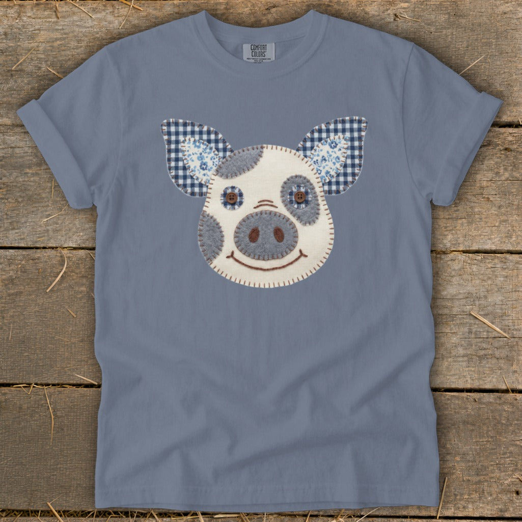 Blue t-shirt with a felt pig face applique featuring checkered ears.