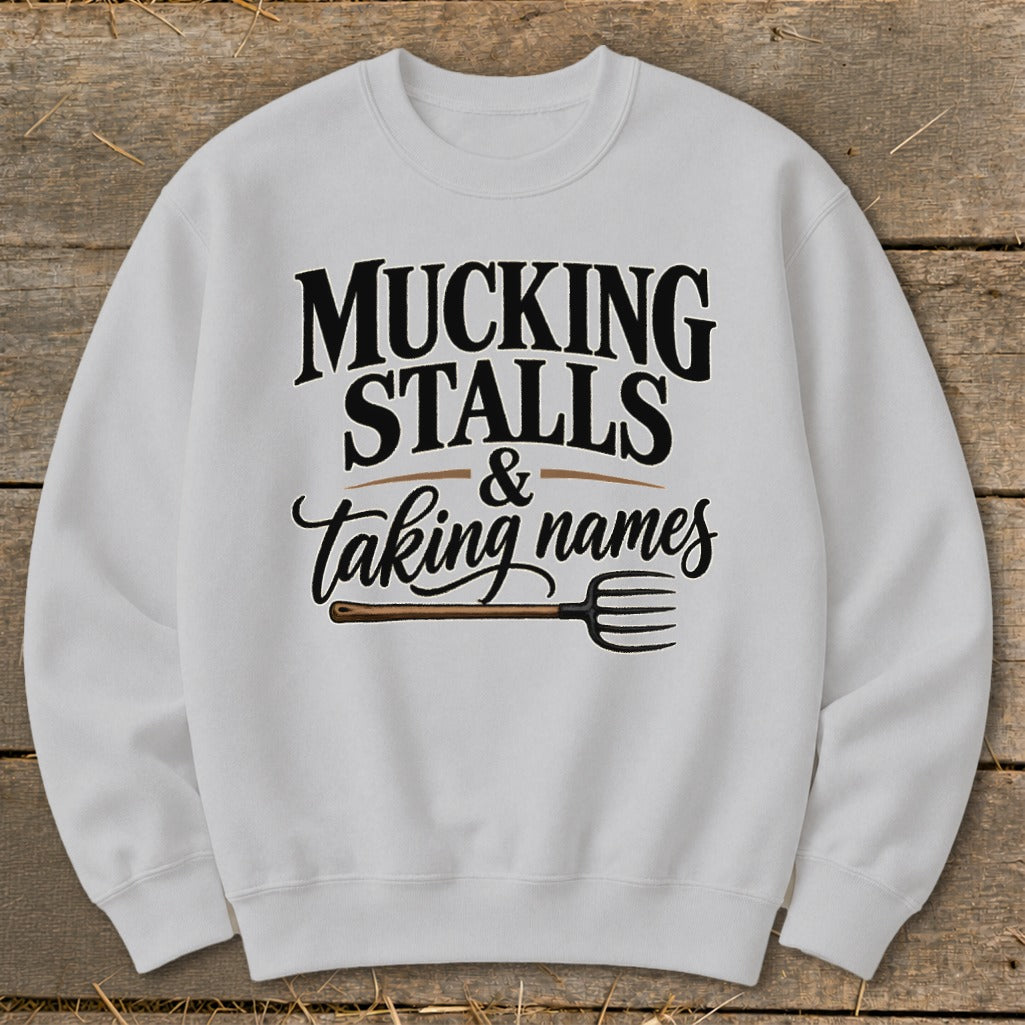 White sweatshirt with "Mucking Stalls & Taking Names" and a pitchfork graphic.