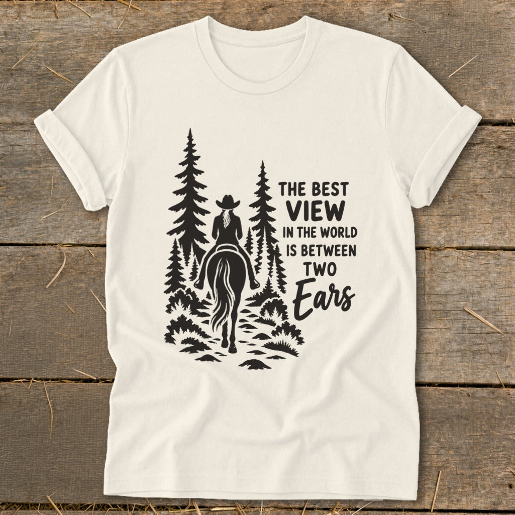 Off-white t-shirt featuring a black graphic of a horse rider in the forest with the text THE BEST VIEW IN THE WORLD IS BETWEEN TWO EARS.