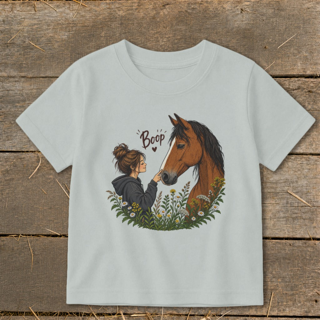 Girl gently touching nose of brown horse with flowers and "Boop" text.