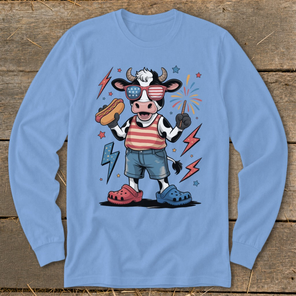 Cartoon cow wearing American flag sunglasses, holding hot dog and sparkler.