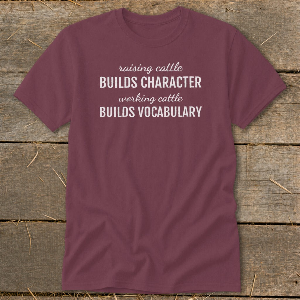 Maroon t-shirt with white text: "raising cattle BUILDS CHARACTER working cattle BUILDS VOCABULARY".