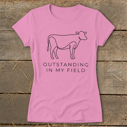 Pink t-shirt with black line drawing of a cow and text "OUTSTANDING IN MY FIELD".
