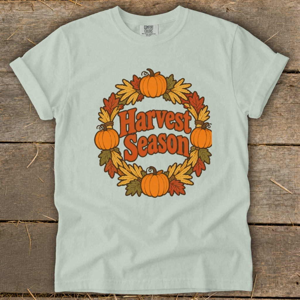 Light green t-shirt with a "Harvest Season" graphic in a wreath of pumpkins and leaves.