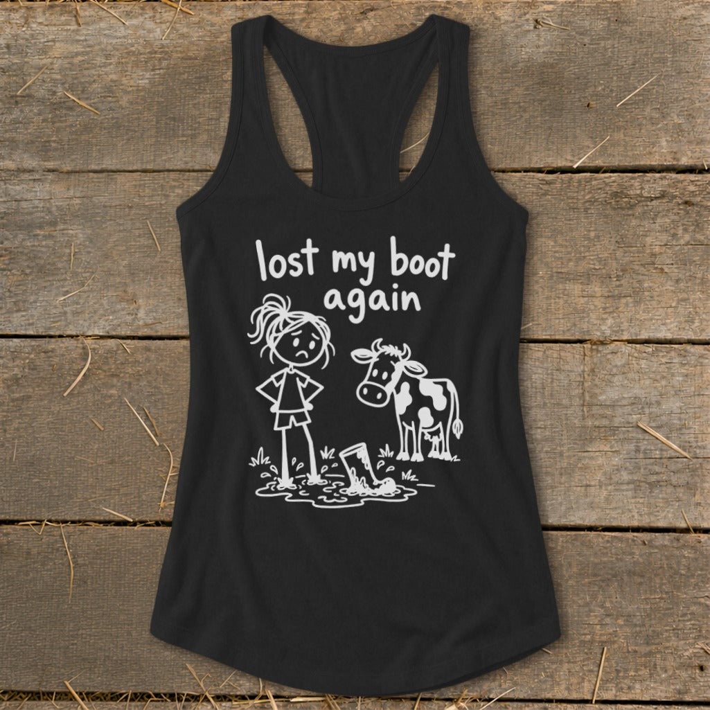Black racerback tank top with white graphic text reading lost my boot again, featuring a stick figure and cow looking at a muddy boot.