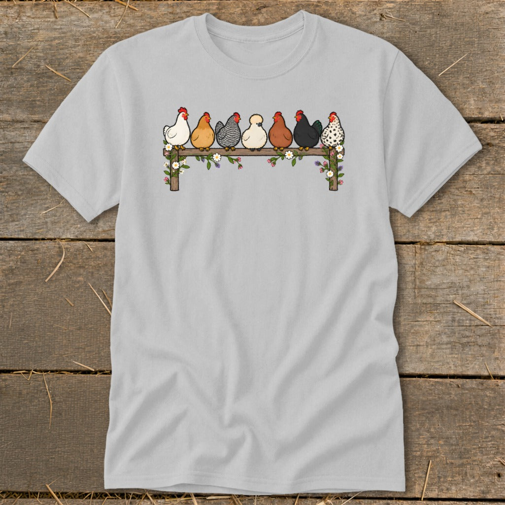 A light gray t-shirt featuring an illustration of seven colorful chickens perched on a flower-decorated wooden fence.